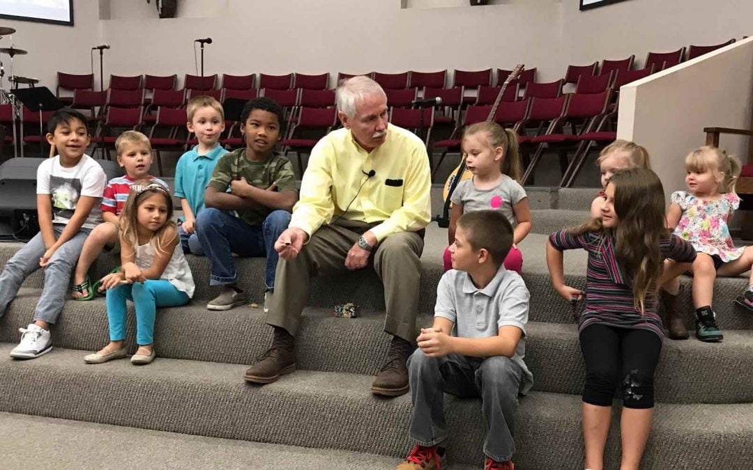 Glen Foster speaking with children at church.