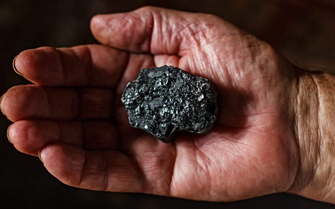 A man holding a piece of coal in his hand