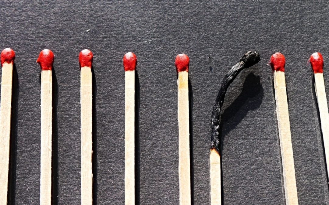 A row of matches with red tops and a single match burned