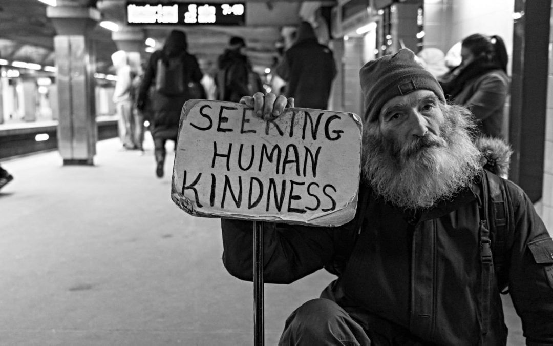 A man holding a sign that says seeking human kindness