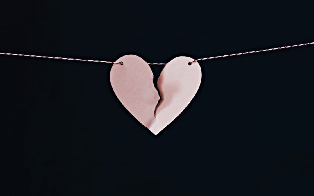 A pink paper heart broken in half hanging on a string
