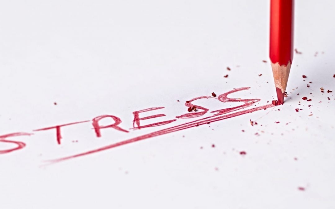 A red pencil writing the word stress on a piece of paper
