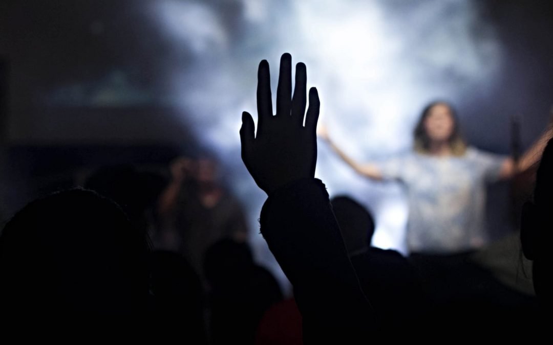 A person holding their hand in the air during a church worship service