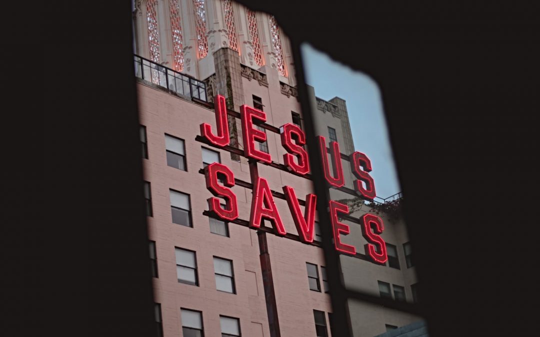 A Jesus Saves sign on metal poles in a city