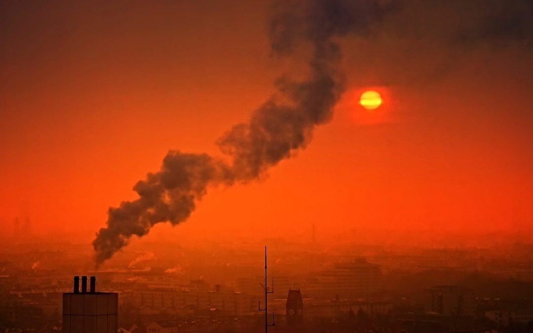 A red sky with black smoke rising from a chimney