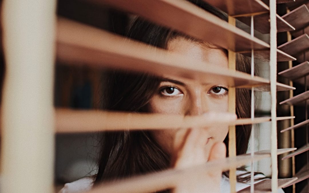 A woman looking through wooden blinds