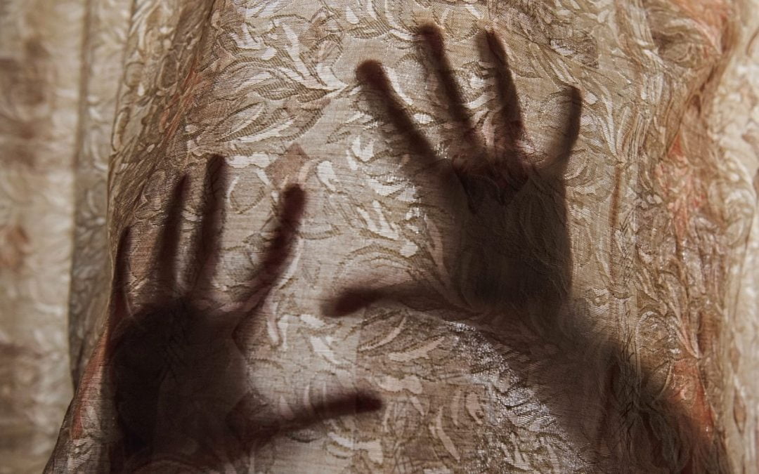 Hands pressed up against a curtain