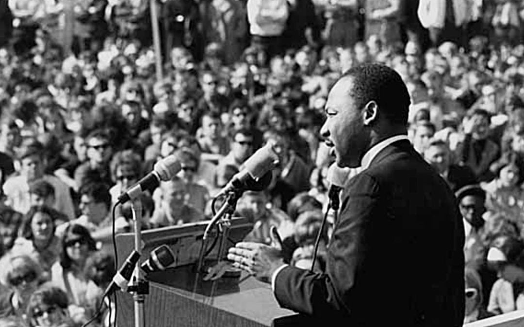 Martin Luther King Jr standing before a crowd giving a speech