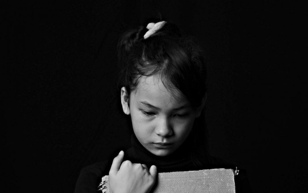 Black-and-white photo of sad girl clutching book