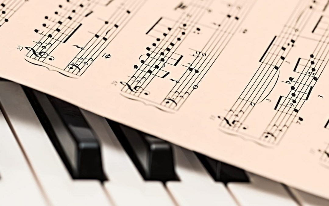 Sheet music resting on piano keys