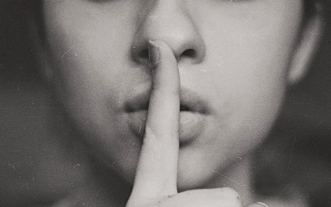 Woman’s lips with raised finger indicating quiet