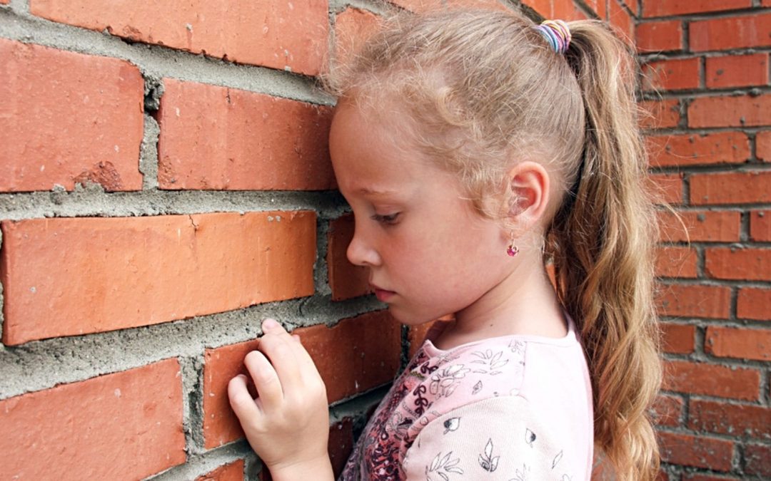 Young girl facing brick wall