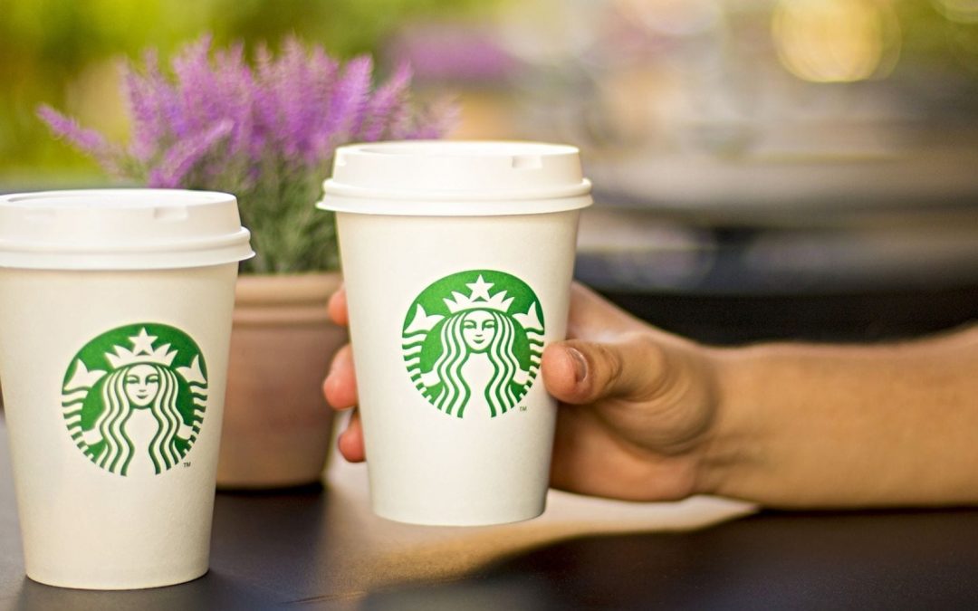 Hand holding one of two Starbucks cups