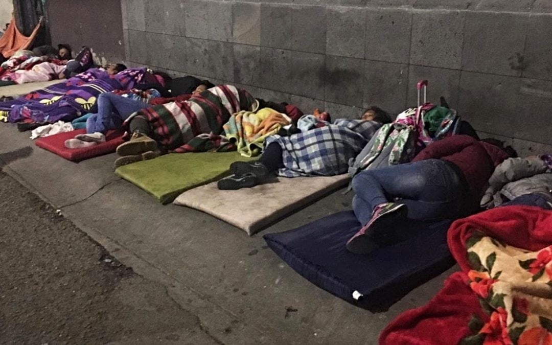 Immigrants sleeping outside with blankets