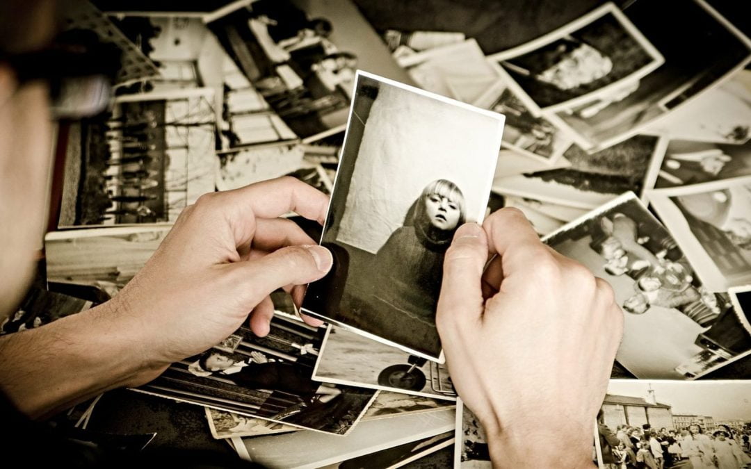 Hands holding an old photograph amid pile of old photos