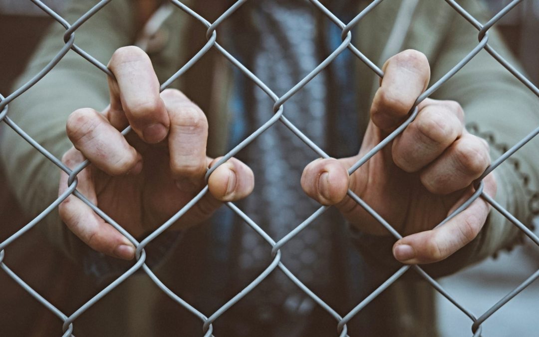 Two hands gripping chain-link fence
