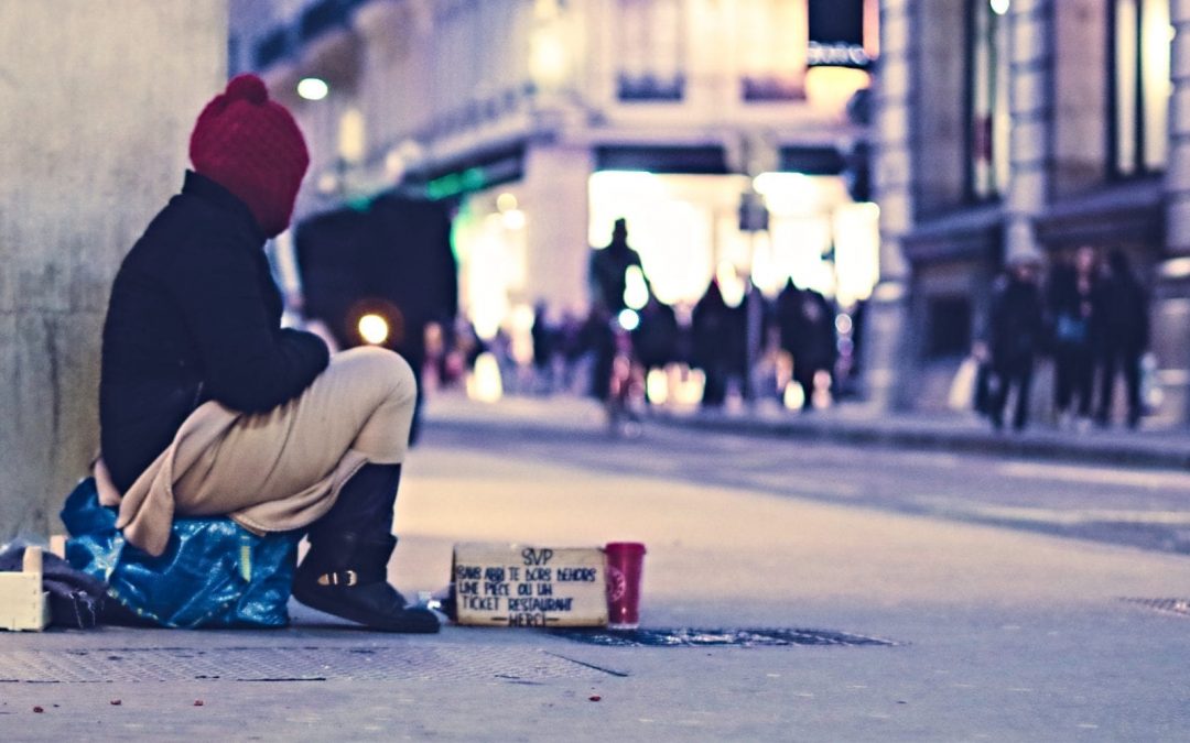 Homeless person sitting on city sidewalk