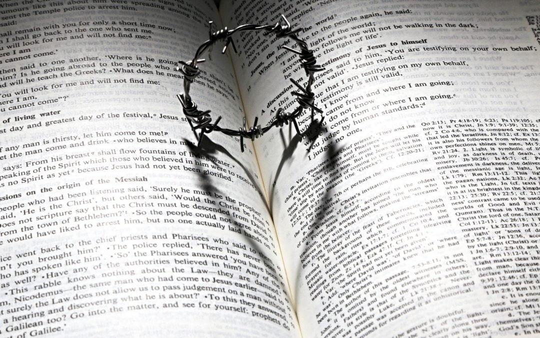 Crown of thorns casting heart shadow on Bible pages