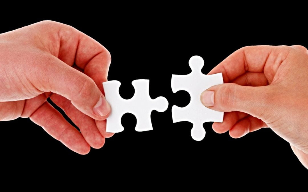 Two hands holding interlocking jigsaw puzzle pieces