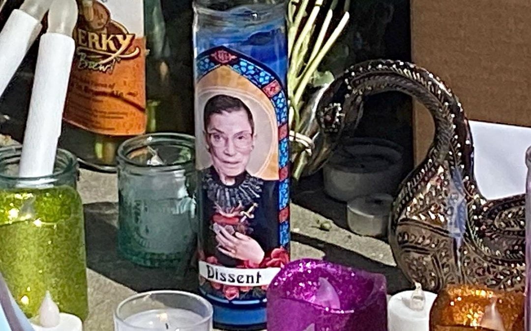 Glass cylinder containing candle and with image of RBG on outside