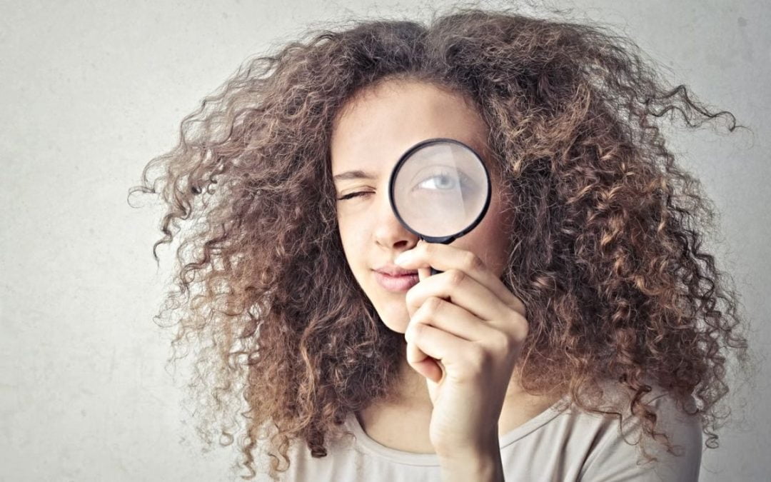 Woman holding magnifying glass to her eye