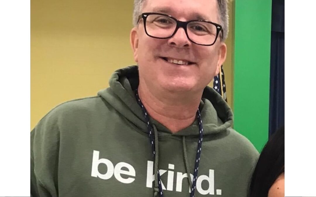 A man wearing a sweatshirt that says, “Be Kind.”
