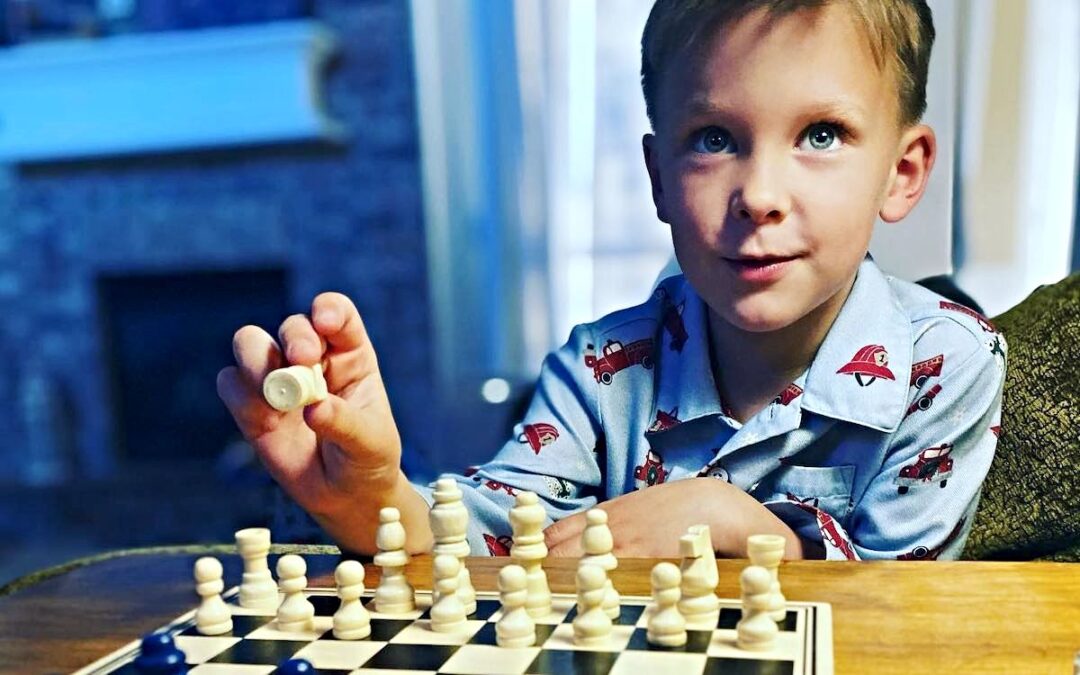 A child sitting at a table playing chess.