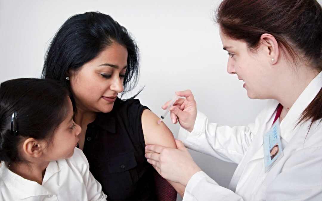 Woman holding child while getting vaccinated