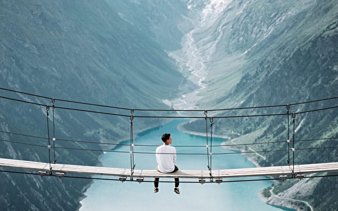 Young man seated on bridge over valley