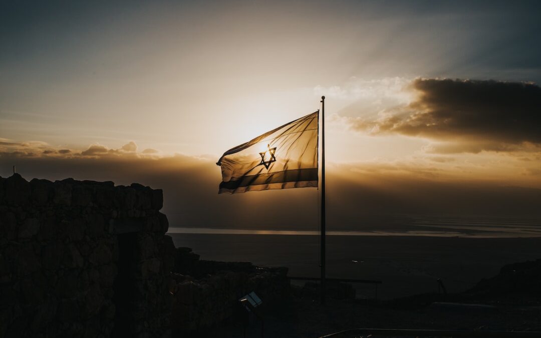 A silhouette of an Israeli flag with the sun setting in the background.