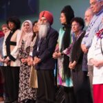 A row of people from several faith traditions standing together on a stage.