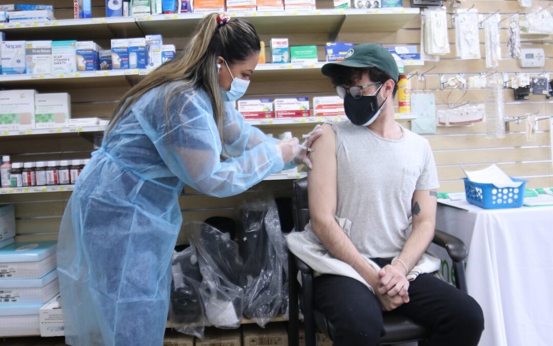 A person sitting in a chair receiving a vaccination at a local pharmacy.