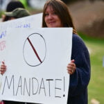 A woman at a protest holding a sign protesting vaccine mandates.