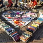 A book sale on the street with books arranged into a heart.