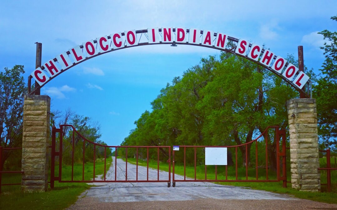 A metal arch over a road with a sign that says, “Chilocco Indian School.”