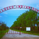 A metal arch over a road with a sign that says, “Chilocco Indian School.”