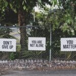 White signs on a chain link fence offering encouragement.