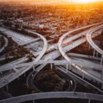 A highway interchange seen from above with the sun rising.