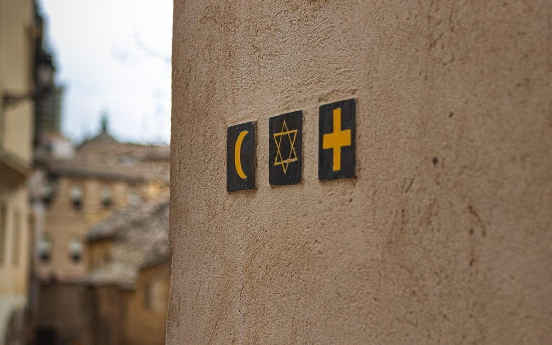 A tan wall with the symbols for Islam, Judaism and Christianity on it.