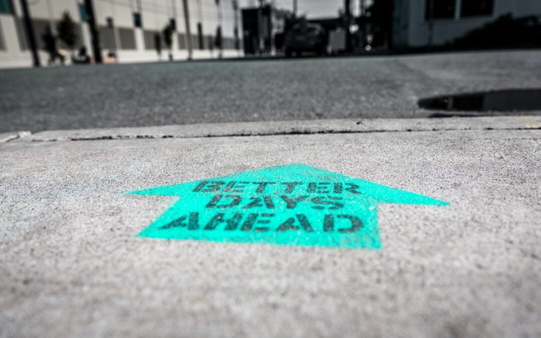 The words “better days ahead” spray painted on a sidewalk.