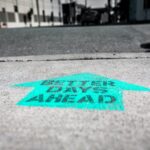 The words “better days ahead” spray painted on a sidewalk.