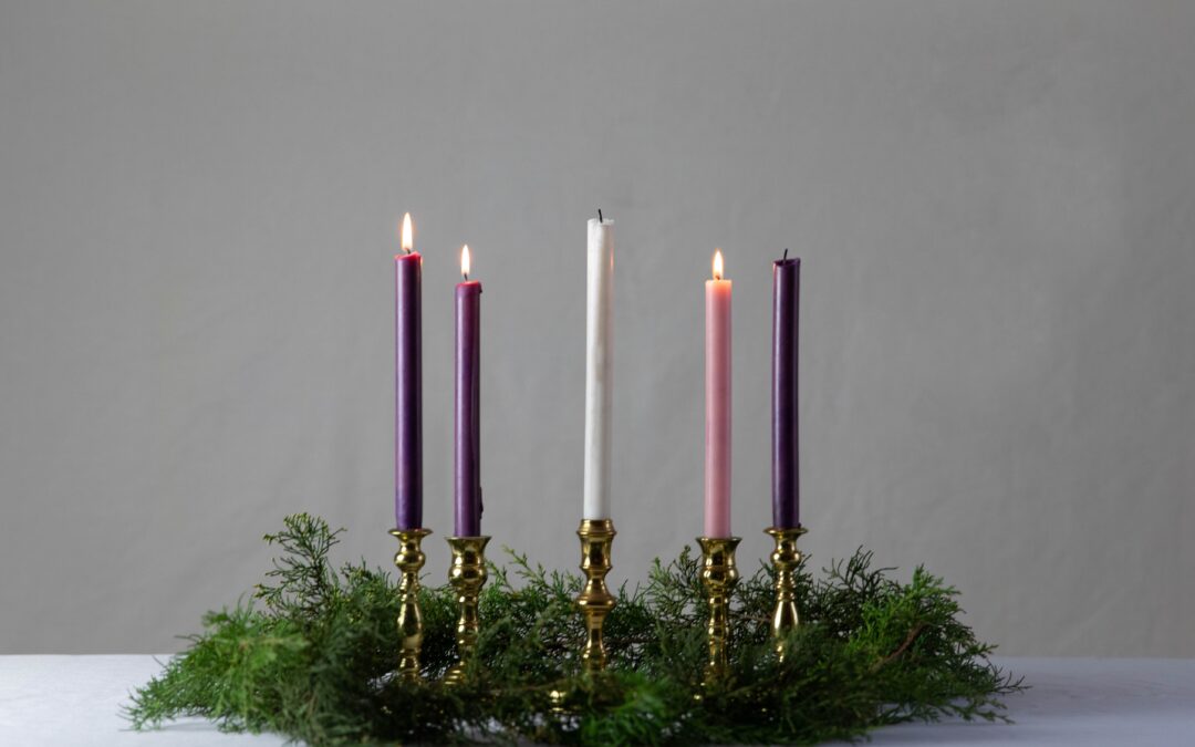 An Advent wreath with three purple candles, one pink and one white candle.
