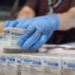 A health care worker stacking boxes of the Johnson & Johnson COVID-19 vaccine.