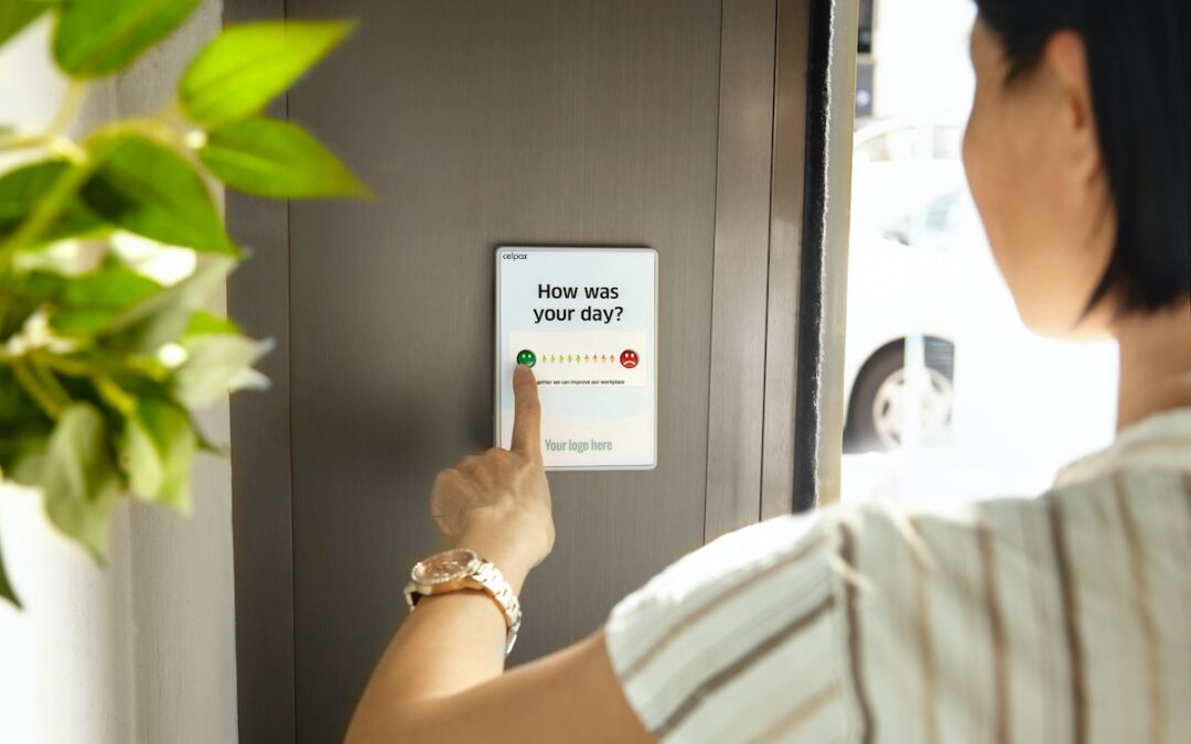 A woman standing by the door of her home pressing buttons on a keypad asking for a rating of her day.