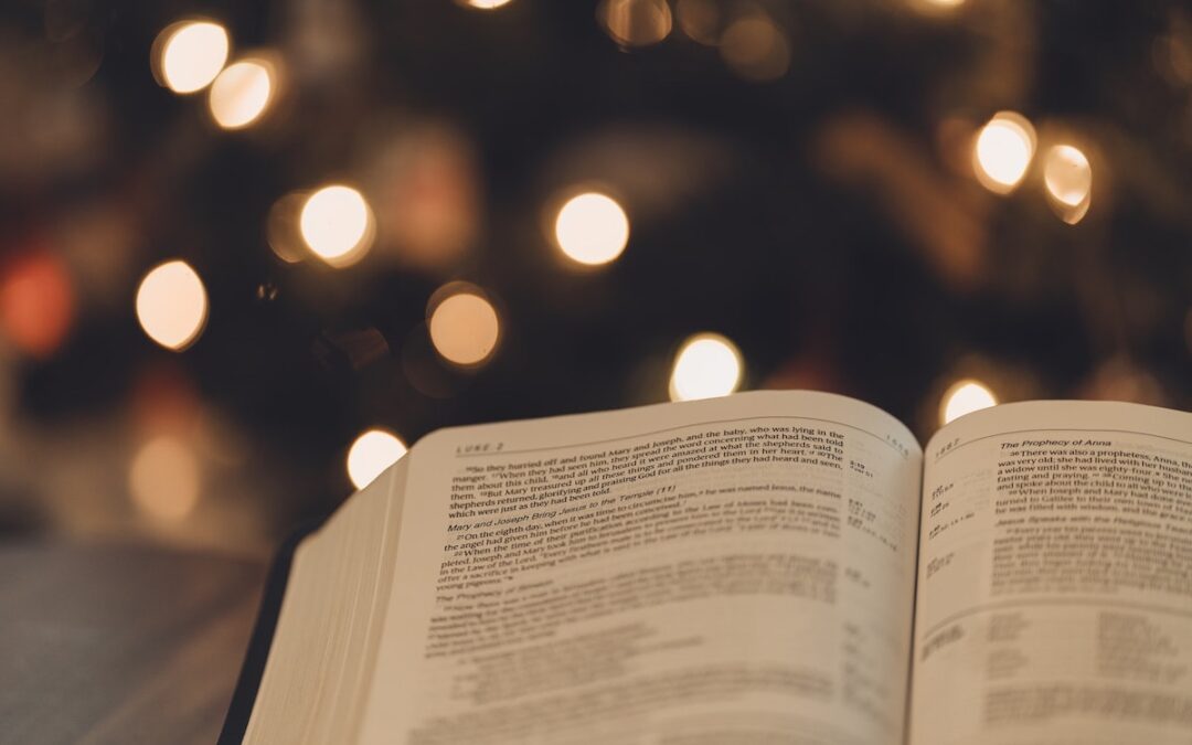 A Bible open to Luke 2 with Christmas lights in the background.