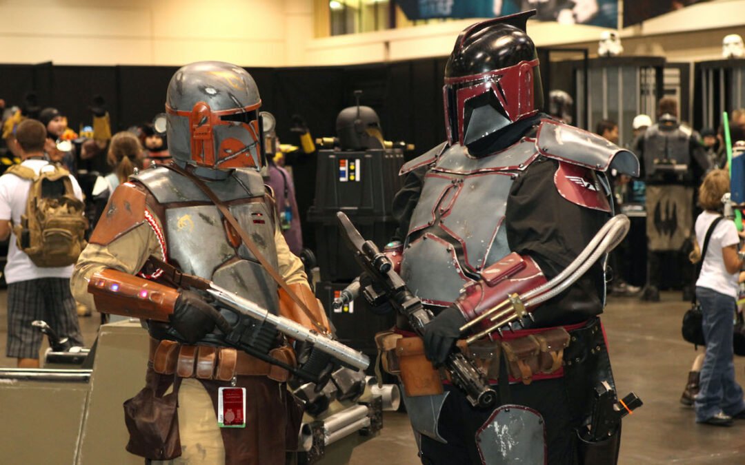 Two people dressed as Mandalorians discussing life at Star Wars Celebration VI.