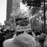 A crowd on the streets seen from behind with a person holding up a sign with a photo of Martin Luther King Jr speaking that says, “I have the same dream.”