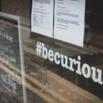 The hashtag #becurious on the window of a store.