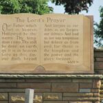 A stone monument with the Lord’s Prayer inscribed on it in a cemetery.