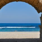 The Mediterranean Sea seen through a stone archway.